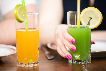 Colorful fruit drinks with a straw on a wooden counter.