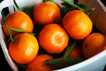 Whole tangerines in a box on a black background