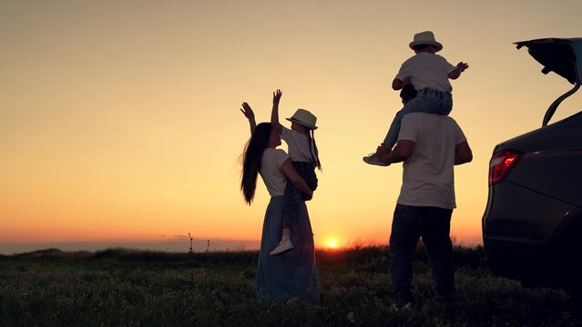 Dad with child, daughter on his shoulders, mom, children dance and admire beautiful sunset. Parents and children stopped at campsite by car. Happy family travels by car. Big family, Travel by car. Kid