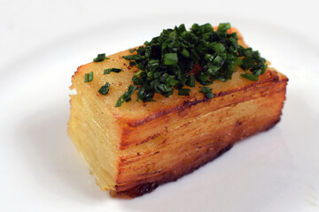 Potato Pave, a potato dish, also known as layered potato or Potato Pavé. Chopped chives on top.