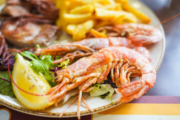 Grilled prawns with salad and golden fries on a plate.
