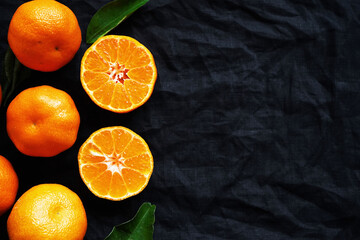 Cut and whole tangerines on a black background