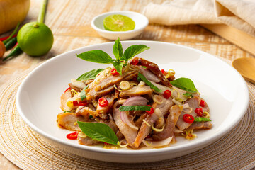 Spicy Grilled Pork Salad with Lemongrass in spicy lime sauce on white plate.(yum moo yang)