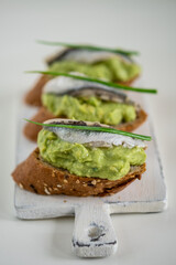 sandwich with anchovy on avocado bed