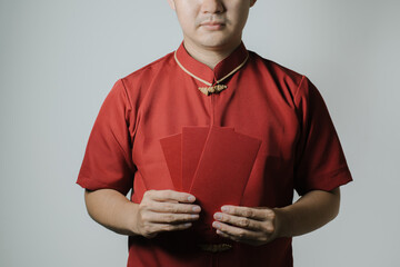 Half face of Asian man wearing Cheongsam or Chinese traditional cloth is holding angpao or red...