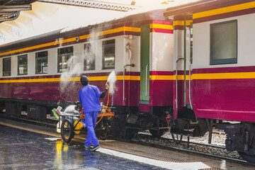 Employee washes railway passenger car, worker washes train cars at train station