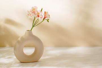 Flower bouquet in stylish vase on the table with sunlight shadows, copy space for design or product...