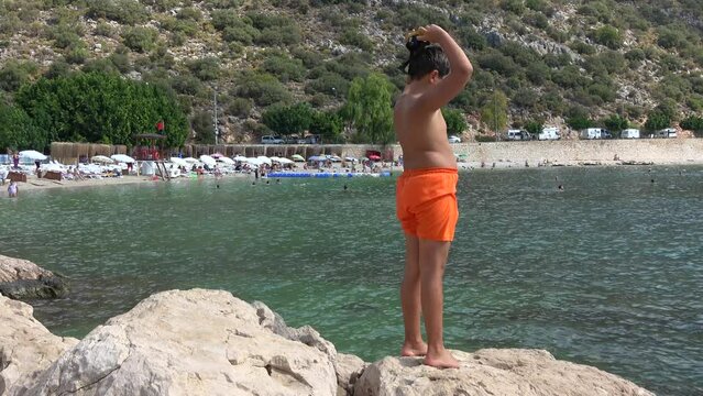 Akcagerme Beach, Kas, Turkey - 7th of September 2023: 4K Chubby boy puts on goggles getting ready to swim 

