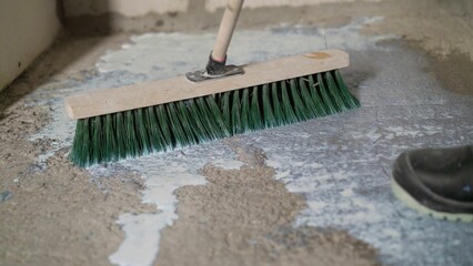 Finishing work - applying a primer or varnish to a concrete surface. The brush cleans the floor...
