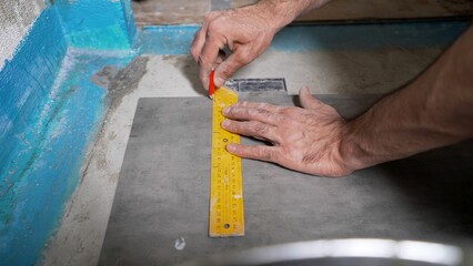 The tiler measures the tiles using a ruler and pencil. Close-up of a construction worker making...