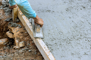 Leveling of new concrete pavement using special working tool by mason worker at construction site
