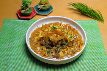 Stew with dried mushrooms and chips on a white plate.