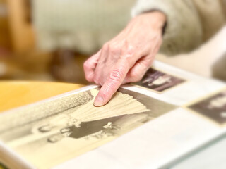 結婚式の写真を指さす高齢女性の手元アップ