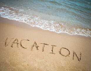Vacation written in a sandy tropical beach