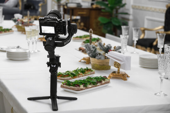 Khmelnytskyi, Ukraine - December 8, 2023: Camera Sony a6500 and DJI Ronin Motorized Gimbal Stabilizer for DSLR or Mirrorless Cameras, buffet table with drinks and snacks. The work of a videographer