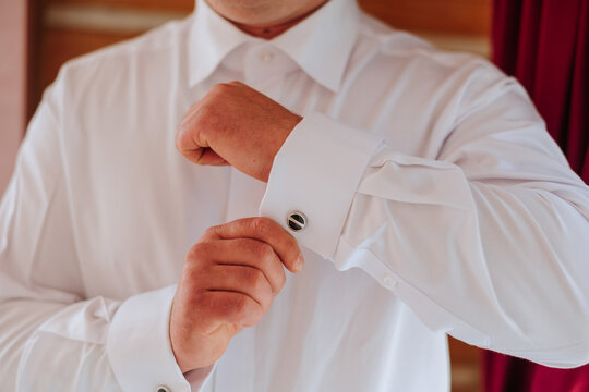 handsome business man buttoning shirt sleeves at home. The groom is preparing for the wedding. Close-up photo.