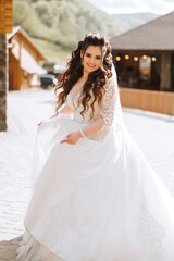 Naklejka premium Curly bride twirls in her wedding dress. Magnificent dress with long sleeves, open bust. Summer wedding