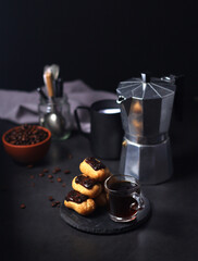 Chocolate eclairs with a cup of coffee and a coffee pot	