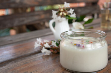 Scented candle and white flowers in natural background. Spa concept