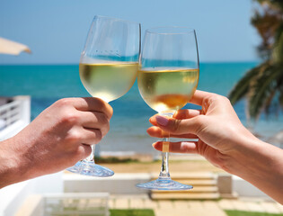 Man and woman clanging wine glasses with white wine