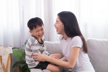 Fototapeta premium Happy family Asian mother and son playing together touching cheeks embracing laughing out loud kidding with fun indoor at home weekend holiday, mom and kid bonding relationship, motherhood tenderness