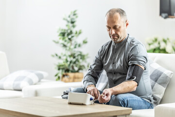 A mature man checking his blood pressure with a digital blood pressure monitor at home