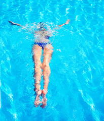 Young woman swimming in a blue water of swimming pool
