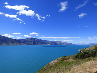 Lake Wanaka, New Zealand on a beautiful sunny day. Calm blue water with mountains in the background and clear skies
