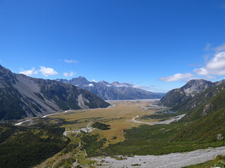 View over valley on Mueller hut track. Southern Alps, South Island of New Zealand, Mt. Cook national park. Snowy mountains on a summer day.