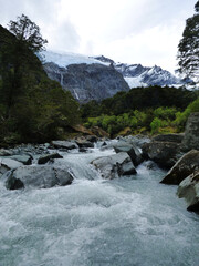 Glacial river under peak of Rob Roy glacier in South Island of New Zealand, Mt. Aspiring National park during the summer day. Snowy mountain in the background.