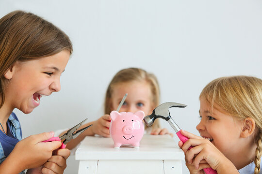 Kids with screwdriver, pliers and hammer by the pink pig piggy bank - Powered by Adobe