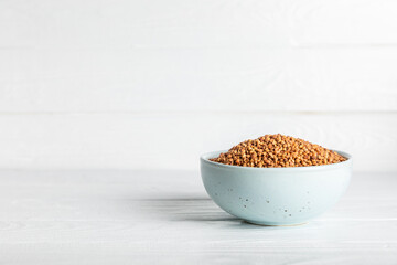 Buckwheat porridge in a bowl on a white wooden background. Healthy food. Diet. Organic cereal.
 Raw buckwheat. gluten free ancient grain for healthy diet. Place for text. Copy space.
