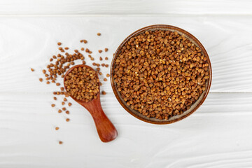 Buckwheat porridge in a bowl on a white wooden background. Healthy food. Diet. Organic cereal.
 Raw buckwheat. gluten free ancient grain for healthy diet. Place for text. Copy space.