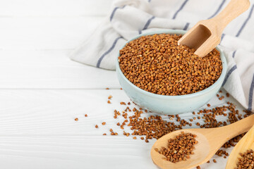 Buckwheat porridge in a bowl on a white wooden background. Healthy food. Diet. Organic cereal.
 Raw buckwheat. gluten free ancient grain for healthy diet. Place for text. Copy space.