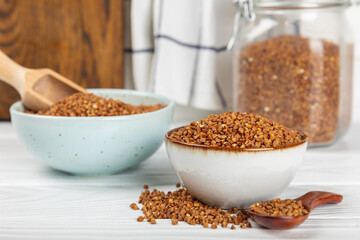 Buckwheat porridge in a bowl on a white wooden background. Healthy food. Diet. Organic cereal.
 Raw buckwheat. gluten free ancient grain for healthy diet. Place for text. Copy space.