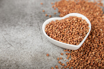 Buckwheat porridge in a bowl on a dark texture background. Healthy food. Diet. Organic cereal.
 Raw buckwheat. gluten free ancient grain for healthy diet. Place for text. Copy space.
