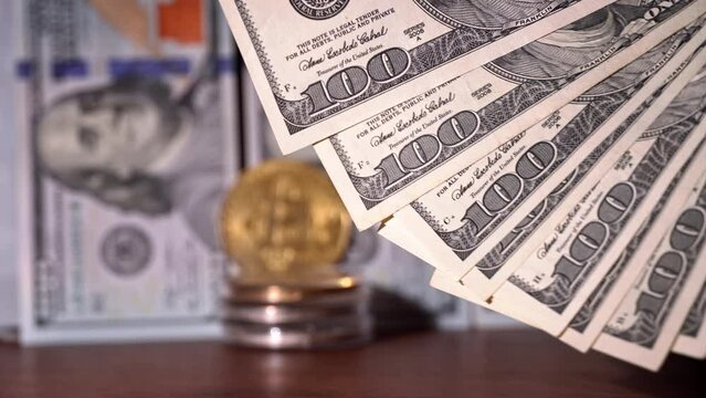 Close-up of man counting out dollars for bitcoins. Bitcoin coin, digital gold next to hands of expert trader counting profitable banknotes in form dollar cash. Cryptocurrency