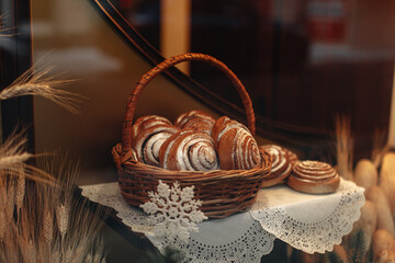 Sweet baked twisted bread buns in a wicker basket. Bakery shop counter