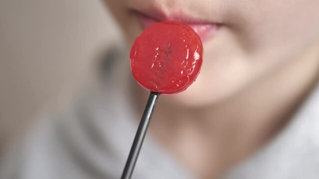 a child licks red candy,