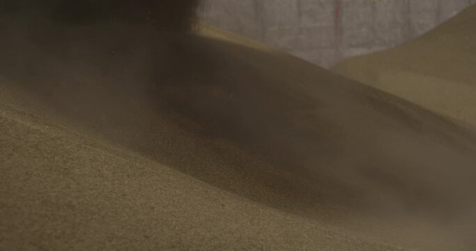 Sand shifts and slides under the wheel of digger truck close up slow motion construction site dust