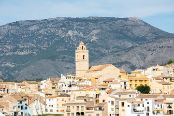 Fototapeta na wymiar View of the town of Polop de la Marina with medieval fortress of Muslim origin and the Church of San Pedro and the high mountains at the back in Marina Baixa, Alicante, Spain
