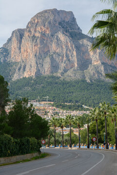 An impressive Ponoig mountain, known locally as &lsquo;el leon dormido&rsquo; seen with tall palm trees from the road to Polop in La Nucia, Spain