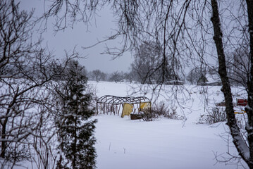 greenhouse covered with snow, trees, garden house and garden accessories