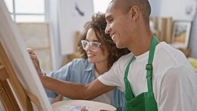 Confident man and woman artists joyfully drawing together at art class in cozy studio