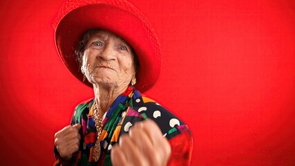 Obraz premium Funny portrait of elderly mature angry aggressive woman trying to fight towards camera, shaking fist, boxing.