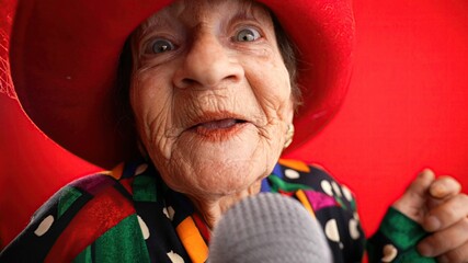 Funny fisheye view of elderly woman singing enthusiastically into a microphone and dancing wearing...
