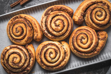Closeup of homemade cinnamon rolls on a gray earthenware tray on gray background