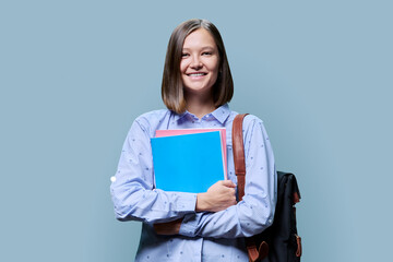 Portrait of smiling female college student looking at camera on blue background