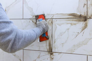 An grouting process, tilers use rubber trowels to fill in spaces between ceramic tiles.