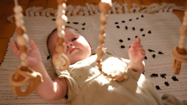 newborn baby plays with a wooden toy. Concept of Childhood, Parenthood.